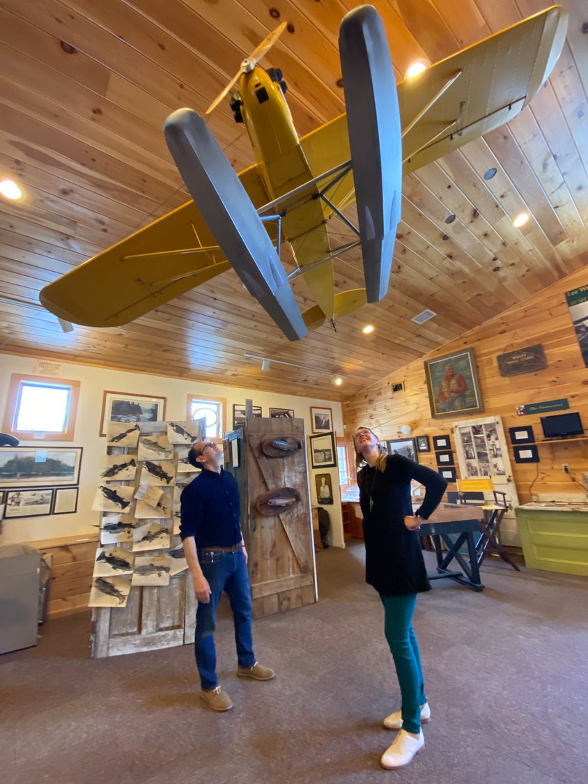 Todd Spire, program coordinator, and Ali Abate, executive director, in the Wulff Gallery at the Catskill Fly Fishing Center and Museum, below the replica Piper Super Cub plane, owned by famed fly fisher Lee Wulff.